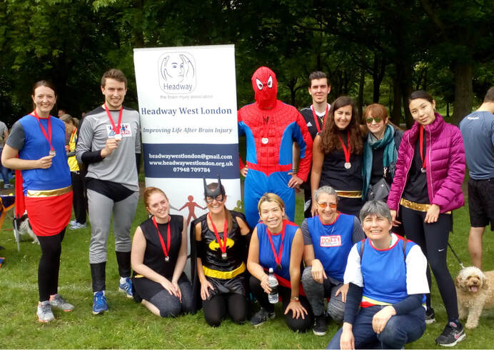 volunteers and linkworkers wearing superhero costumes and posing with Headway poster