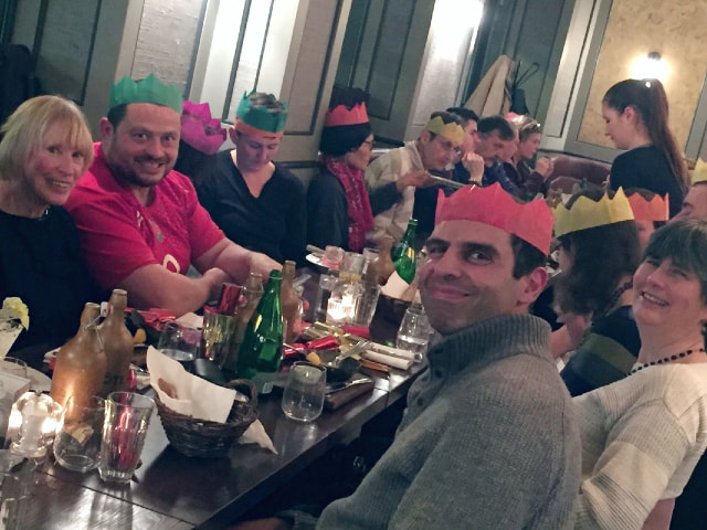 group gathered at dinner table, wearing christmas paper crowns