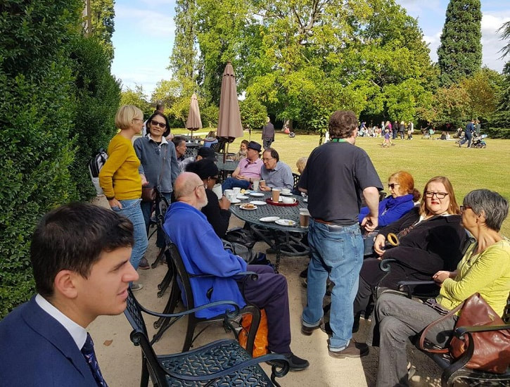 people sitting outside around tables in park