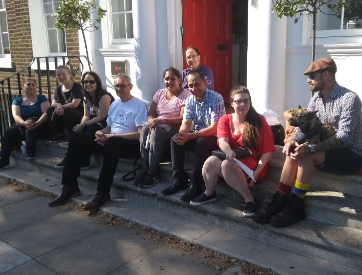 group sitting on steps in front of building with red door